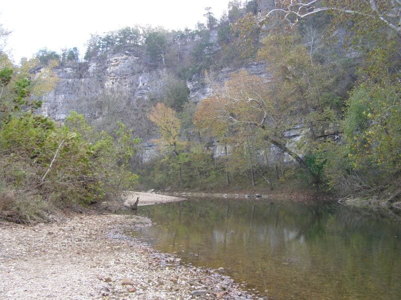 The Buffalo River flows past the Pruitt landing with wooded Ozark hills rising beyond the riverbank.