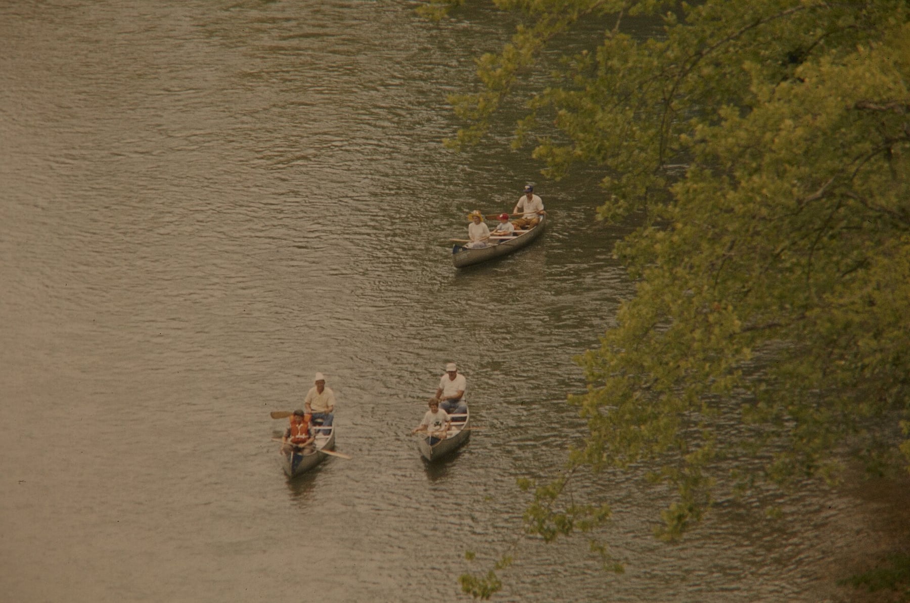 Visitors paddle canoes through a wooded Ozark National Scenic Riverways corridor.