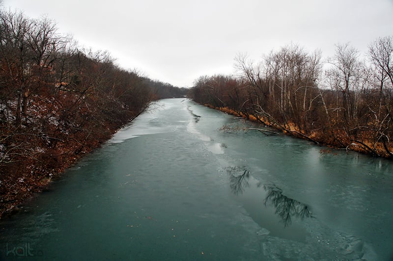 The James River flows past a low wooded bank and calm water in Springfield, Missouri.