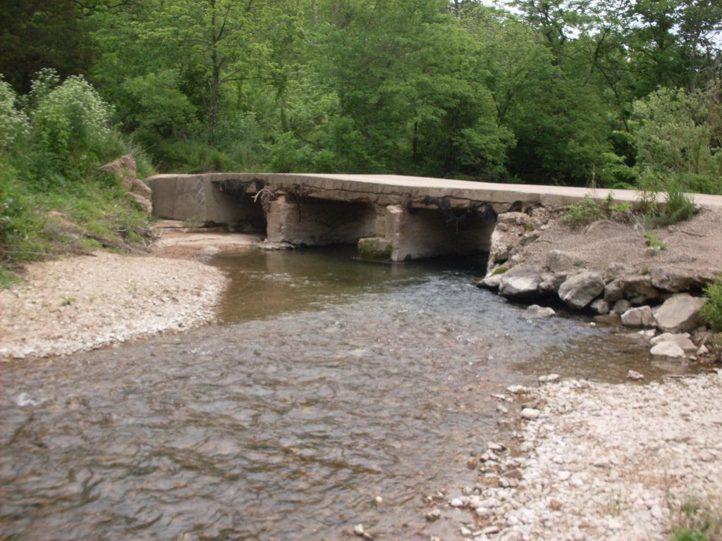 A county road bridge crosses the narrow upper North Fork River between wooded banks.