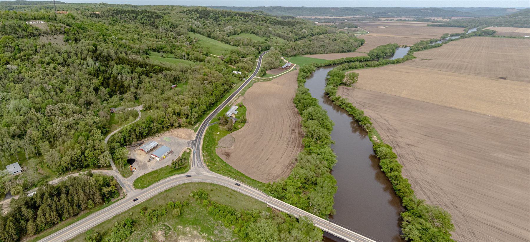 The Root River near Houston reflects bright clouds with trees lining both sides of the channel.