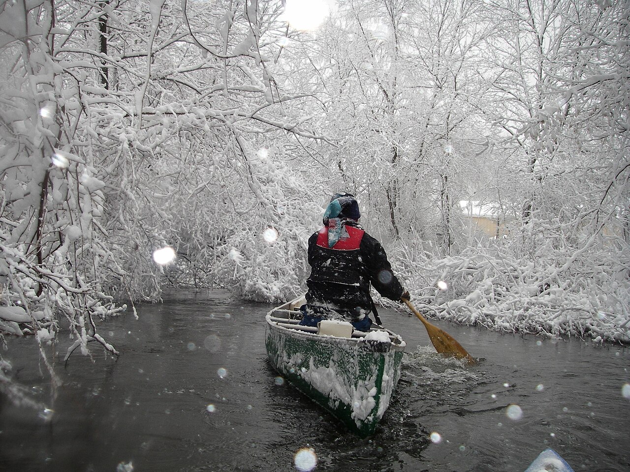 A paddler moves through a snowy Shiawassee River corridor near Holly, Michigan.