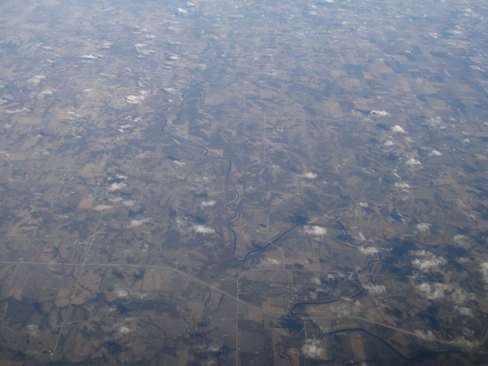 The Skunk River flows between wooded banks with exposed roots and late-season leaves along the water.